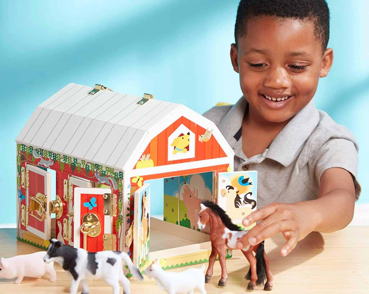 Jongen speelt met speelgoedboerderij van Melissa & Doug met dieren en deurtjes