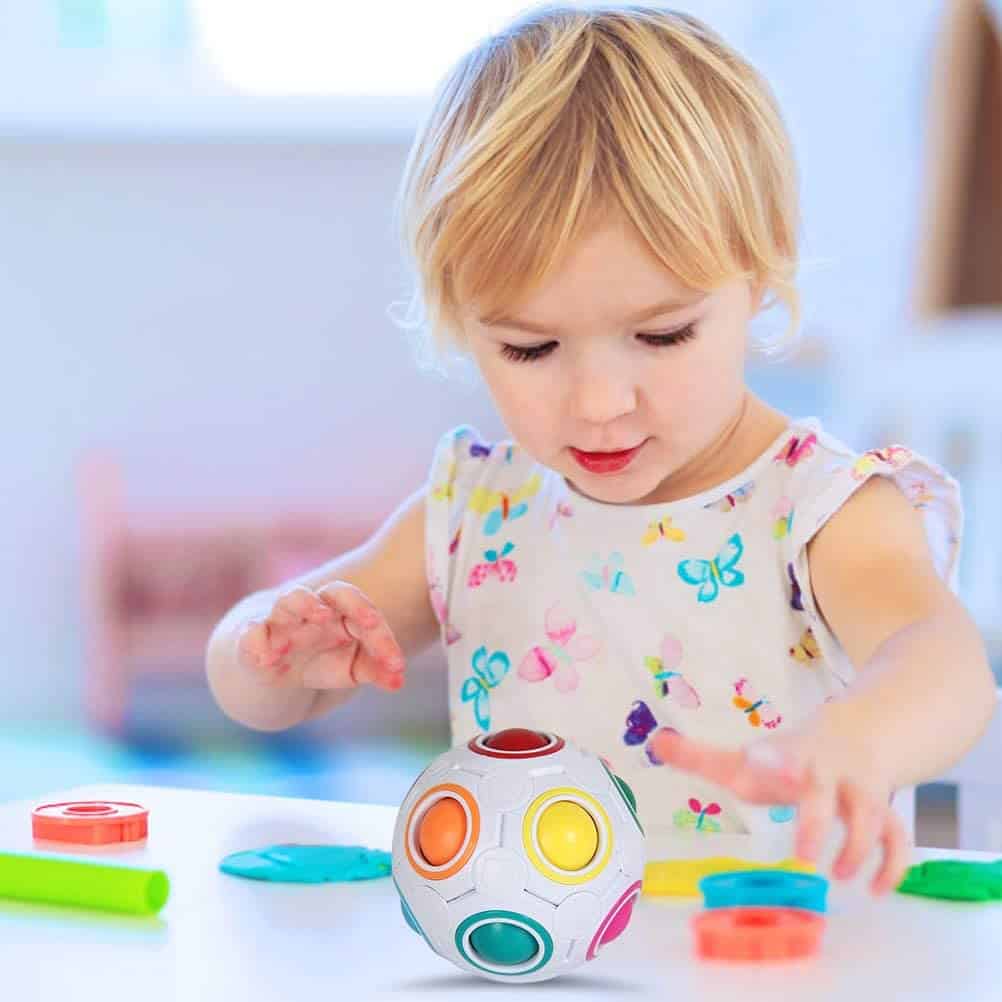 Meisje speelt met regenboog puzzel bal